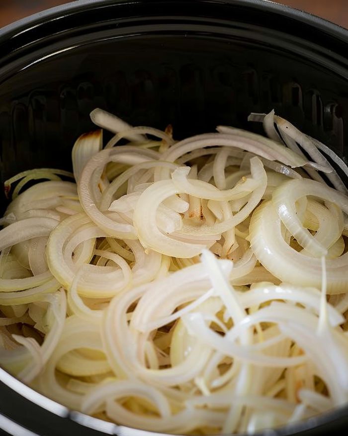 Toss the onions into the bottom of your slow cooker & pop pork chops on top. But hold on—the real magic is in the sauce that's coming up